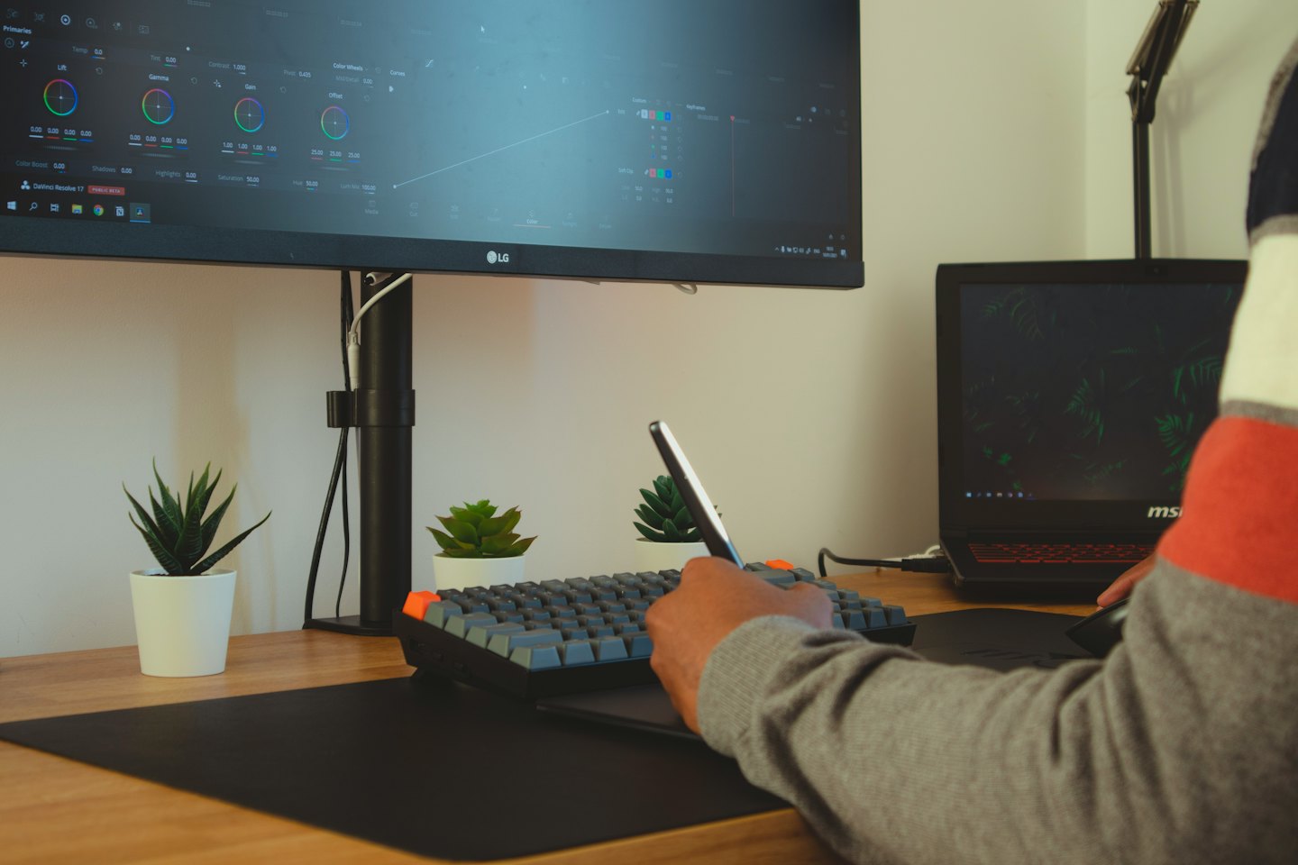 Graphic designer uses a stylus and tablet at a wooden desk.